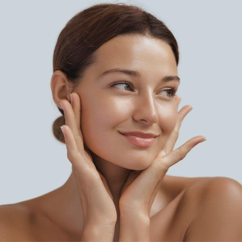 A woman with natural looking beauty holding her face.